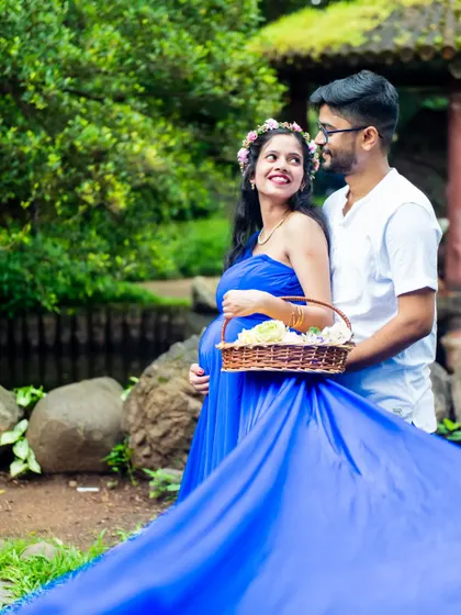 The flowing train of this royal blue maternity gown creates a stunning visual effect. It adds a touch of drama and elegance to the portrait, set against the natural beauty of the park.
