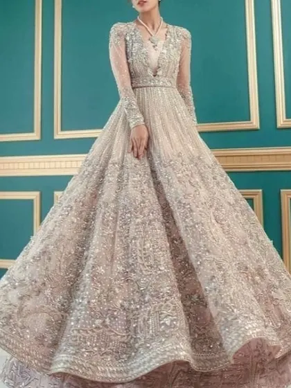 An ethereal, heavily embellished gown with long sleeves. The intricate beadwork and sequins create a dazzling effect, perfect for a grand entrance.