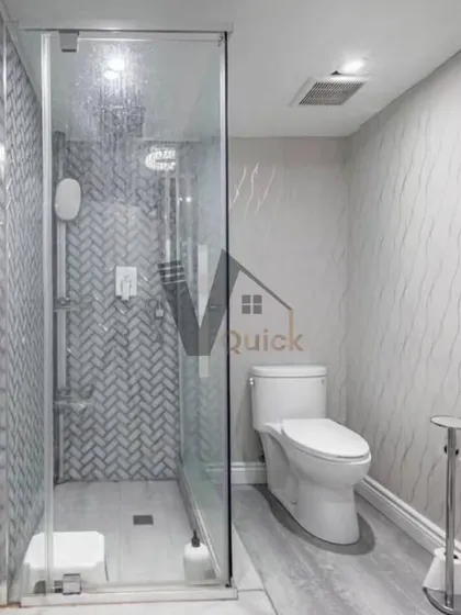 Simplicity and elegance define this modern bathroom. A walk-in shower with a herringbone tile pattern is the star, complemented by soft, textured wallpaper. The glass partition keeps the space feeling open and bright.