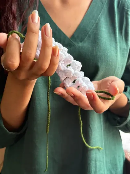 Holding the gajra so you can see the detail in each little crocheted flower. I use a soft cotton yarn to create this delicate, handcrafted hair accessory.