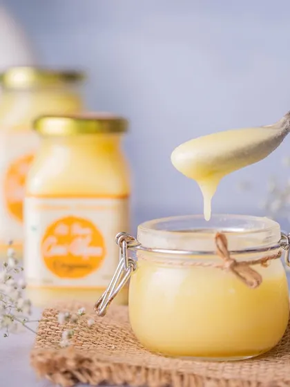 An enticing drip shot for a brand of A2 Cow Ghee. This image focuses on the pure, smooth texture of the ghee, communicating quality and richness in a single moment.