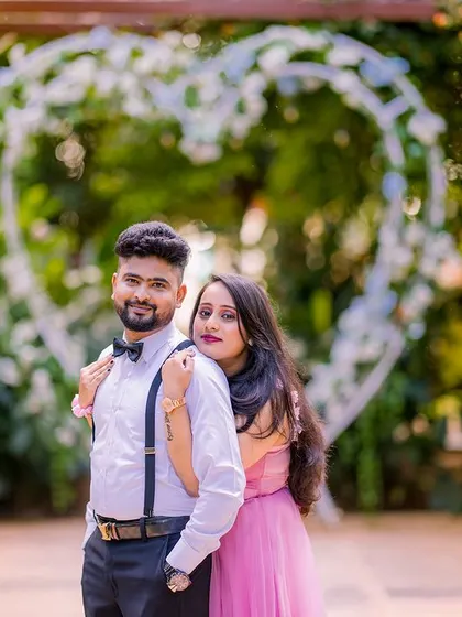 A lovely portrait of a couple in front of a heart-shaped arch. The groom's suspenders and bow tie add a touch of vintage charm to their look.