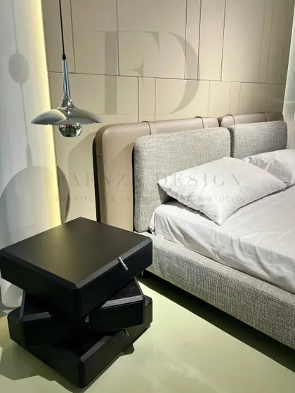 A detail shot of the unique bedside table, designed as a stack of three rotating black boxes. This piece is both a functional nightstand and a sculptural object, showcasing our innovative approach to furniture design.