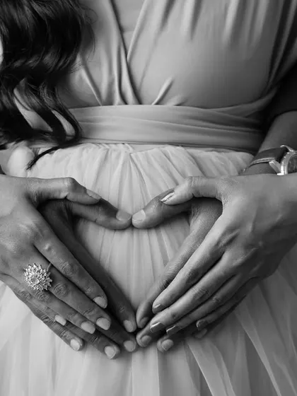 A close-up on the heart of the matter. This artistic shot focuses on the couple's hands forming a heart on the baby bump, a simple and beautiful symbol of their love.