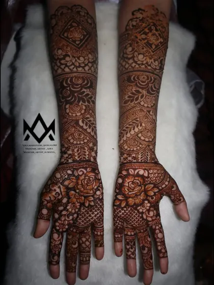 An engagement bride's full arm mehendi, combining floral work on the palms with geometric and traditional bands on the forearms.