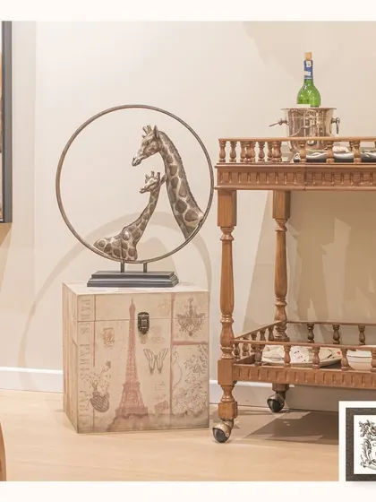 This giraffe sculpture, paired with a vintage-style trunk and a classic bar trolley, creates a well-traveled and eclectic corner. The mother and child design adds a heartwarming touch.