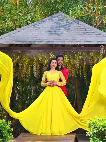 The flowing trails of the yellow gown create a beautiful frame around the couple in this garden pre-wedding shot.
