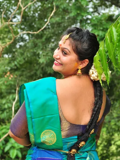 An over-the-shoulder candid shot taken outdoors, capturing a natural and happy expression. Using the green foliage as a backdrop adds a fresh and lively feel to the portrait.