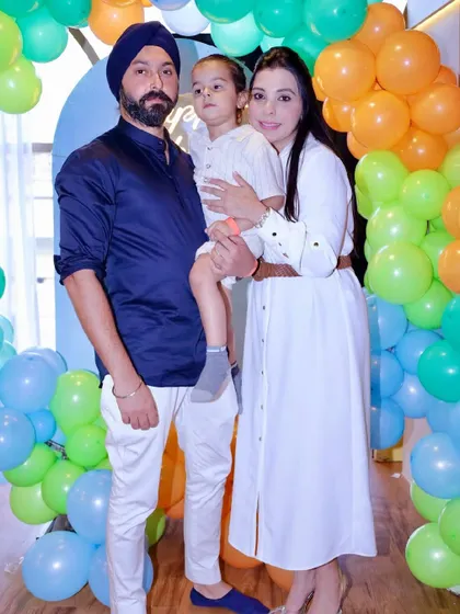 A family portrait in front of a colorful balloon backdrop.