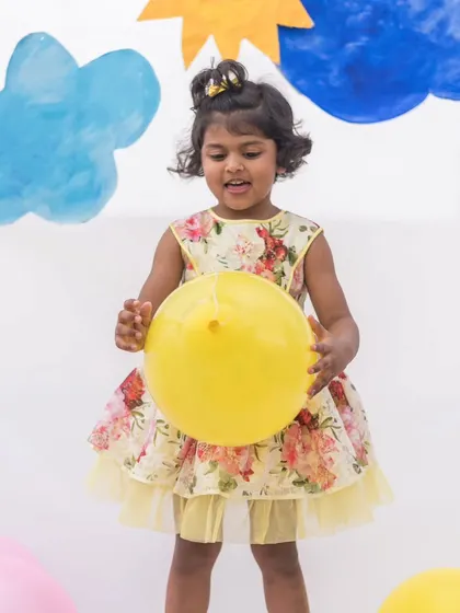 Sunshine and flowers come together in this cheerful yellow party dress. It features a beautiful floral print and a light tulle underskirt for extra volume, perfect for a garden party.