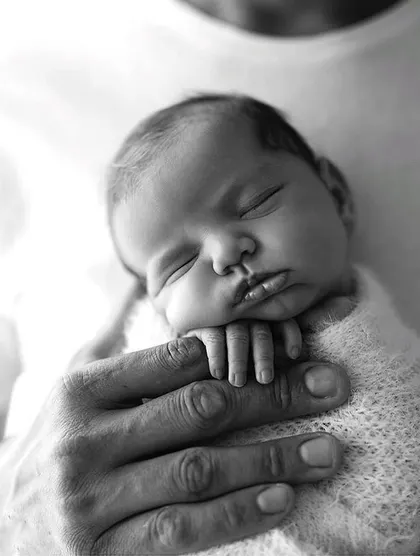 The comfort of a parent's touch. This image showcases the gentle and secure way we handle newborns, capturing a moment of pure peace and trust.