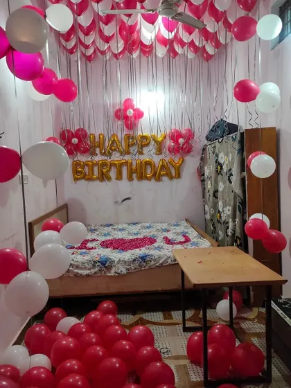 A simple room decoration for an 18th birthday. The setup includes pink and white balloons on the ceiling, a shimmer curtain, and foil letters.