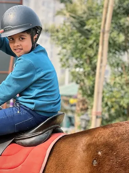 A young rider gives a peace sign, showing how much fun he's having. Our goal is to make every lesson an exciting adventure.