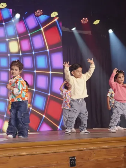 A young performer takes center stage, arms raised in a moment of pure expression. This shot captures the individual confidence that blossoms within our group dance activities.