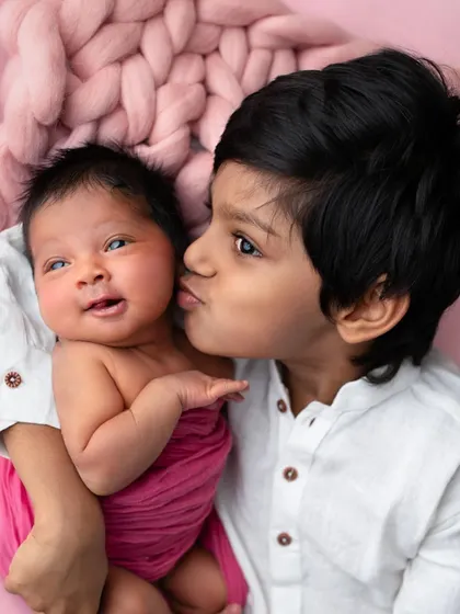 A gentle kiss from a big brother to his newborn sister. These unscripted, tender moments are what make sibling portraits so deeply meaningful.