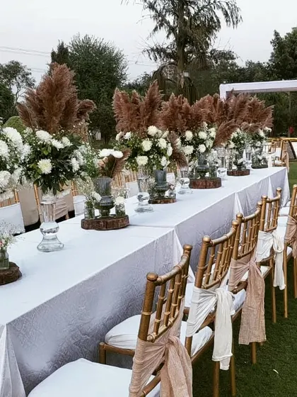 Details matter, and this boho-themed table setting shows my commitment to creating a complete aesthetic. The arrangement includes pampas grass, white florals in classic urns, and wooden accents on a crisp white tablecloth for a chic, rustic look.