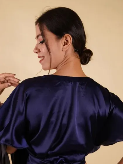 A stylish navy blue satin blouse with bell sleeves and a tie-waist detail. This versatile piece can be worn as a blouse or a top.