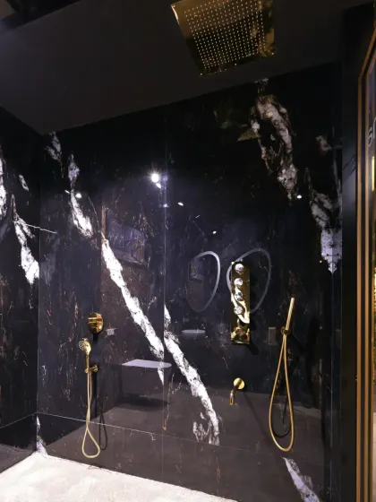 The shower area continues the bold theme with floor-to-ceiling black marble and luxurious gold fixtures.