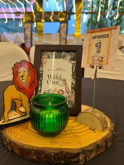 A 'Little Wild One' centerpiece featuring a lion cutout, a green candle, and a personalized name card.