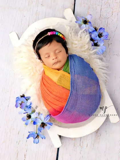 A full view of the rainbow baby setup on a miniature white bench.