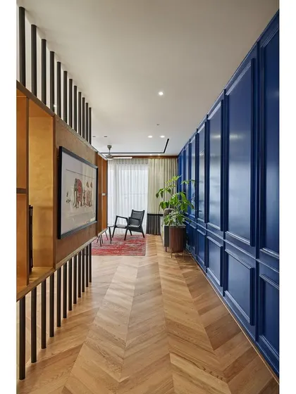 The entryway of the "Blue is the Warmest Colour" apartment. A striking Parisian-style paneled wall in a warm blue hue conceals doors and sets a sophisticated, intriguing tone for the entire home.