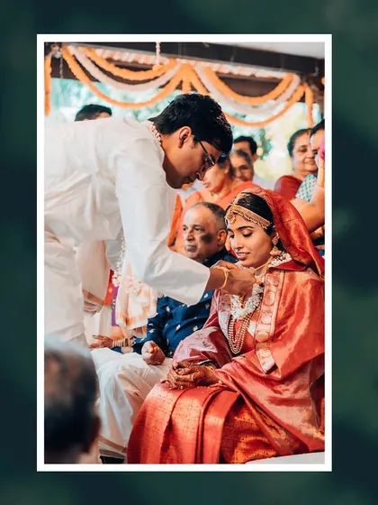 A close-up of a key ritual during a wedding ceremony, with the groom placing the sacred necklace on the bride.