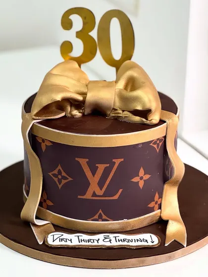 Thirty and thriving with a touch of luxury. This Louis Vuitton inspired cake is all about style and class, featuring the iconic monogram and a beautiful handcrafted golden bow.