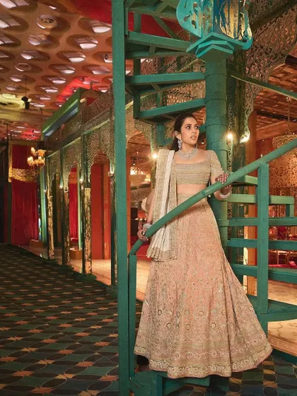 The full view of the peach lehenga by Abu Jani Sandeep Khosla, set against a stunning architectural backdrop. The environment always enhances the story of the outfit.