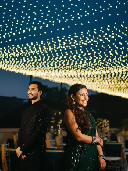 A stylish portrait of the couple standing back-to-back under the beautiful night sky decor. It showcases their individual style while highlighting their connection.
