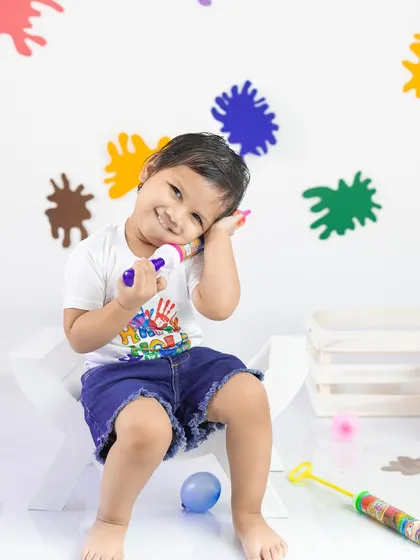 A splash of color for Holi. This little boy is having a great time with his pichkari (water gun) in this fun and safe studio setup for the festival of colors.