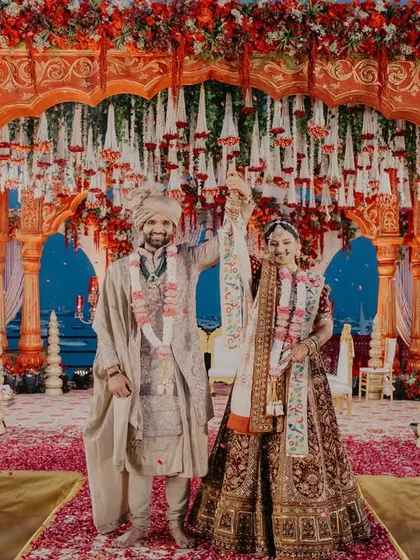 The couple celebrating under a shower of petals after their vows, surrounded by priests performing the traditional aarti.