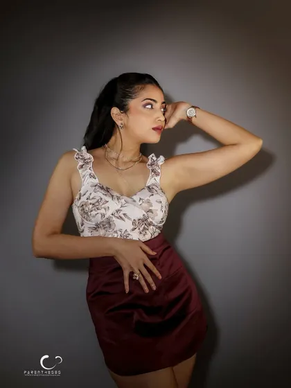 A classic studio pose that exudes elegance. The lighting is soft yet directional, highlighting the details of her outfit and the graceful curve of her posture.