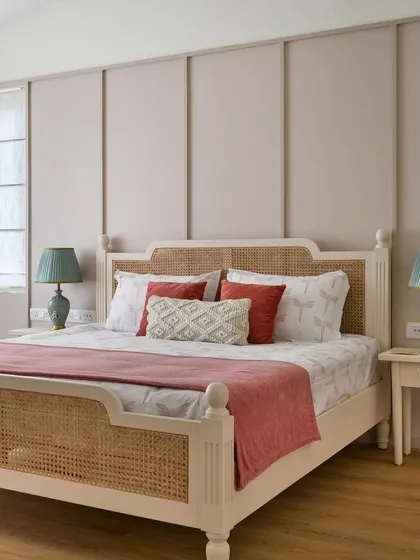This bedroom from 'House of Kismish' is a French-inspired affair with a delicate pastel hue. The custom-made bed with a cane headboard and footboard is set against a paneled wall, creating a soft and alluring ambiance.