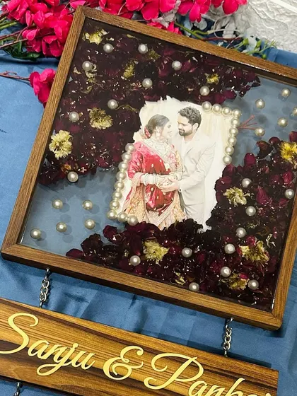 The main 12-inch frame preserves the couple's varmala petals around their photo, with pearls scattered for an elegant touch.