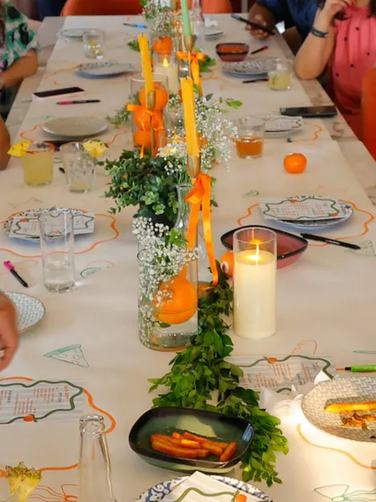 The tablescape for the citrus-themed shower featured a runner of fresh greenery, oranges, and baby's breath, with tall, elegant candles adding a warm and intimate glow.