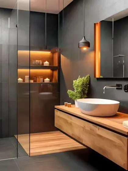 A moody and sophisticated bathroom design with dark slate tiles and warm wood accents. The floating vanity and vessel sink are illuminated by pendant lights, creating a dramatic and spa-like atmosphere.