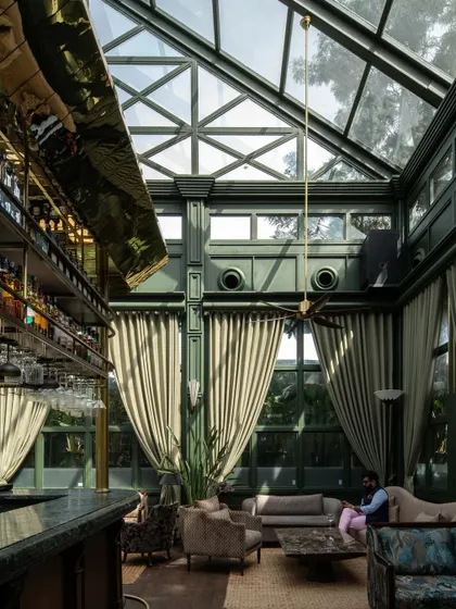 The grand scale of the Lord Elgin Glasshouse is evident in this view, showing the relationship between the bar, the lounge seating, and the full height of the glass walls and ceiling.