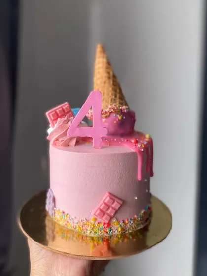 How cute is this ice cream cone drip cake? It's a fun and colorful design for a 4th birthday, complete with sprinkles and chocolate bar decorations.