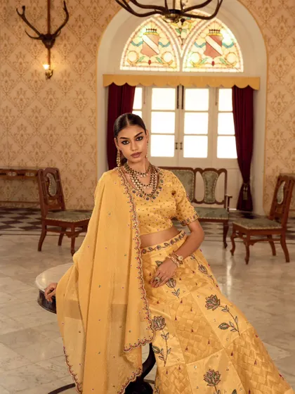 A classic three-quarter portrait for a brand campaign. The soft lighting and elegant pose beautifully showcase the yellow lehenga and intricate jewelry.