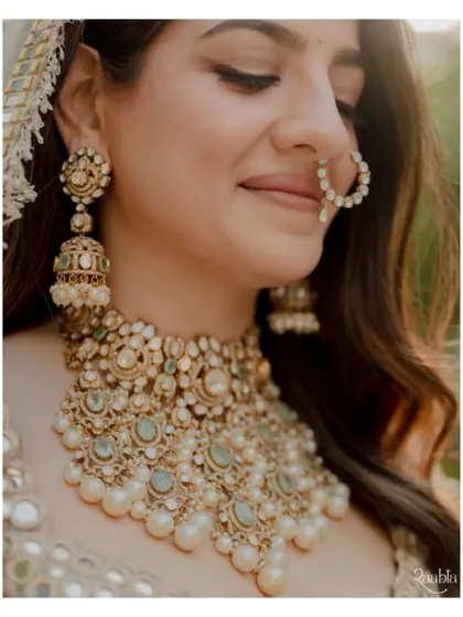 A close-up of the bride's beautiful jewelry and serene expression, highlighting the details of her traditional wedding look.