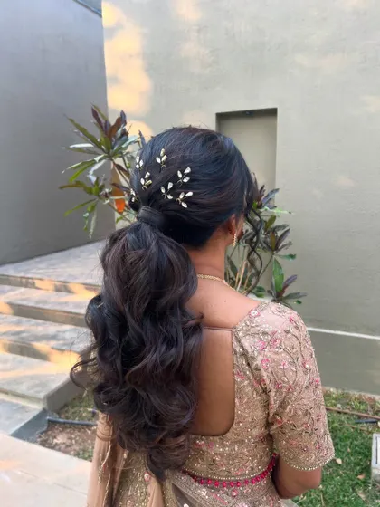 A back view of the elegant low ponytail, showing the placement of the delicate hairpins.