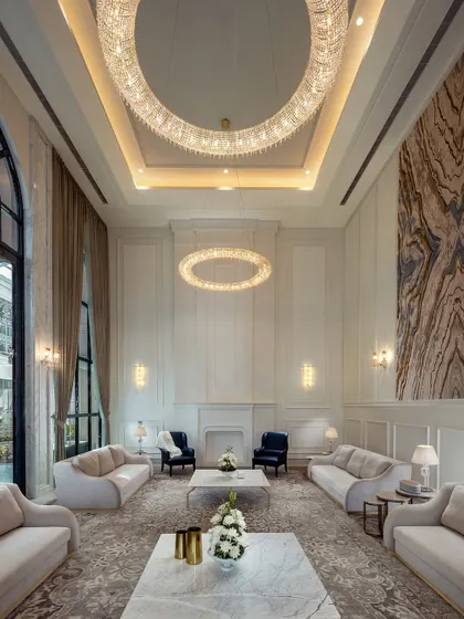 This double-height living room, with its halo-like crystal chandeliers and symmetrical arrangement, is a sanctuary of quiet luxury. The neutral color palette and classical wall paneling create a space that is both grand and calming.