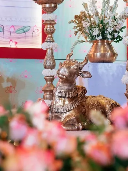 Traditional brass elements like the Nandi statue and tall diyas (lamps) are central to our South Indian decor. They are surrounded by fresh flowers, adding a touch of divinity and cultural richness.
