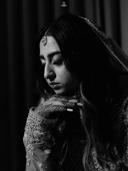 A dramatic black and white portrait of a Muslim bride, capturing a moment of quiet contemplation.