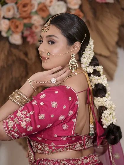 A unique view from the back, showcasing a beautiful floral braid hairstyle and the intricate details of the blouse, earrings, and maang tikka.