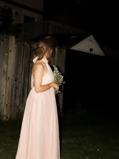 A side view of the elegant pink gown, highlighting its backless design.