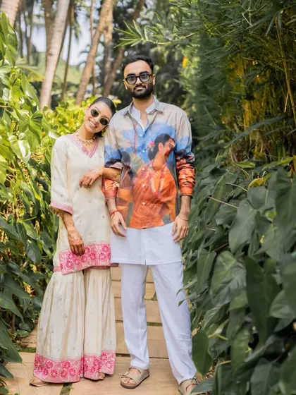 The couple looking effortlessly chic in their coordinated outfits for a Goa Mehendi. His printed shirt and her sharara set are perfect examples of comfortable yet stylish destination wedding wear.