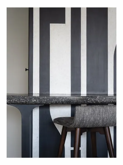 This custom bar table features a terrazzo top and is set against a bold, graphic art panel. The design is minimal but impactful, creating a stylish corner for entertaining that feels integrated with the home's overall aesthetic.