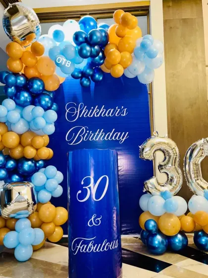 The full view of the "30 & Fabulous" birthday setup, showcasing the custom blue backdrop and the vibrant orange and blue balloon arch.