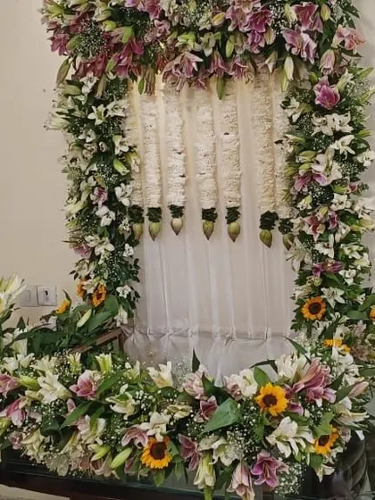 A full view of a Ganpati mandap decorated with an abundance of fresh lilies, sunflowers, and hanging floral strings.